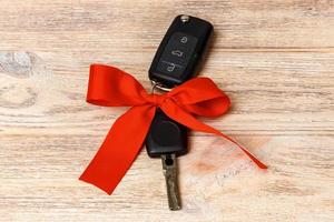 Close-up view of car keys with red bow as present on wooden background photo