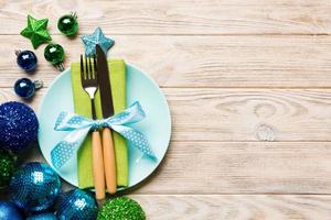 Holiday composition of Christmas dinner on wooden background. Top view of plate, utensil and festive decorations. New Year Advent concept with copy space photo