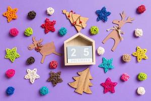 Top view of wooden calendar. The twenty fifth of December. New Year decorations on purple background. Festive stars and balls. Merry Christmas concept photo