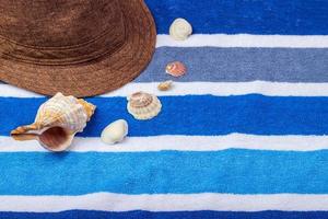 una composición de vacaciones de verano en una toalla de playa con conchas marinas y un sombrero. foto