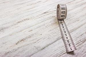 Close up tailor measuring tape on wooden table background. White measuring tape shallow dept of field photo