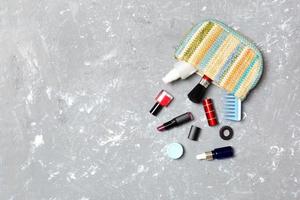 Make up products spilling out of cosmetics bag on grey cement background with empty space for your design photo