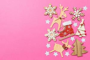 Top view of pink background decorated with festive toys and Christmas symbols reindeers and New Year trees. Holiday concept with copy space photo