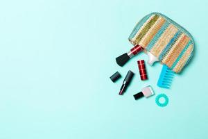 Make up products spilling out of cosmetics bag, on blue pastel background with empty space for your design photo