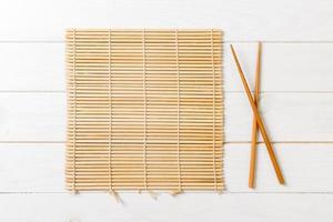 two sushi chopsticks with empty bamboo mat or wood plate on wooden Background Top view with copy stace photo