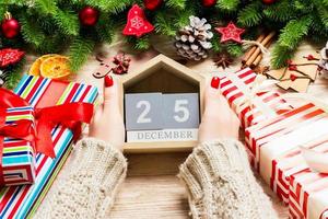 Top view of female hands holding a calendar on wooden background. The twenty fifth of December. Holiday decorations. Christmas concept photo