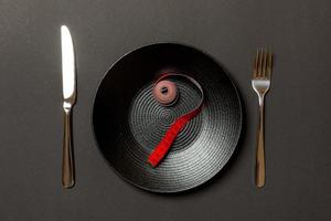 tenedor y plato con cinta métrica sobre fondo de color. concepto de dieta foto