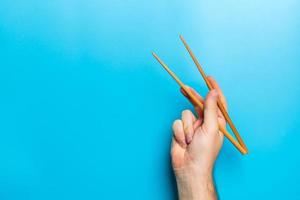 Wooden chopsticks in male hand on black background with empty space for your idea. Tasty food concept photo