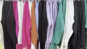 Clothes of different colors hang on hangers in store. video