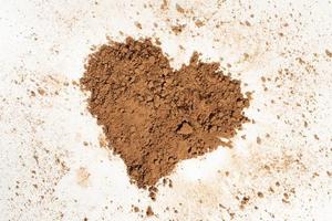 Cacao en polvo vertido en forma de corazón, aislado sobre fondo blanco. foto