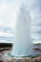 el gran géiser, géiser en el suroeste de islandia, valle de haukadalur. géiser saliendo del suelo contra el fondo de un cielo nublado foto