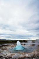 The Great Geysir, geyser in southwestern Iceland, Haukadalur valley. Geyser splashing out of the ground against the background of a cloudy sky photo