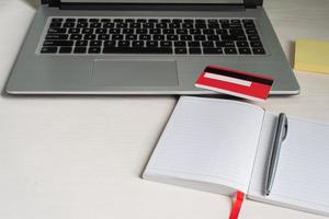 computadora portátil, cuaderno abierto, bolígrafo, tarjeta de crédito, nota de papel foto