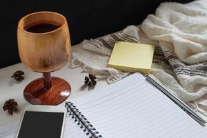 A wooden cup of juice, paper note, note book, smartphone photo