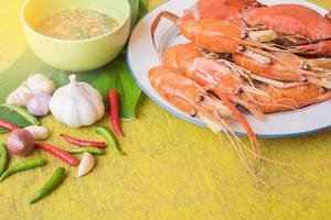 conjunto de basura al vapor y gambas con salsa de marisco sobre mesa de madera amarilla foto