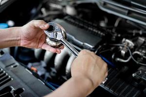 llave de cierre en la mano un hombre con cambio de filtro de aceite en el concepto de servicio de sala de máquinas de coche foto