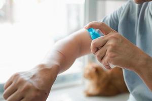 A man is spraying alcohol on a cat scratch wound Cleaning and disinfection , First aid concept in home photo