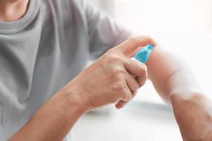 Asia man is spraying alcohol to arm for cleaning from a cat scratch wound and disinfection in First aid concept bleeding wounds photo