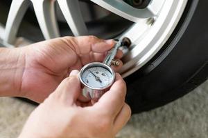 Car basic check ,close up A man hold air pressure gauge check tire air pressure of wheel in service concept photo