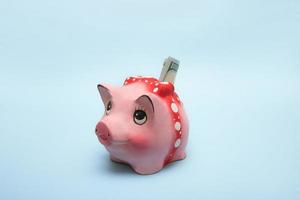 piggy bank with a banknote stuck in on a light blue background photo