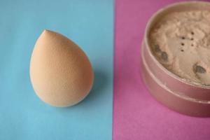 Beauty box, set of female cosmetics, crumbly matte mineral powder and blush with a beauty blender for makeup on a blue pink and purple background. Flat lay. Top view photo