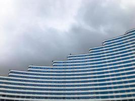 urban landscape against the backdrop of a cloudy sky. house of different heights, with rolls on roof, non-uniform building size.  building in the form of a wave. in the city center in blue and white photo