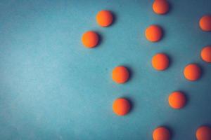 Small yellow orange beautiful medical pharmaceptic round pills, vitamins, drugs, antibiotics on a blue background, texture. Concept medicine, health care. Flat lay, top view photo