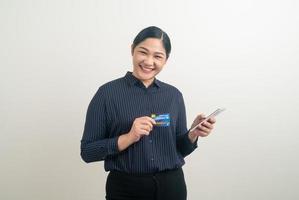 mujer asiática que usa un teléfono inteligente con una tarjeta de crédito en la mano foto