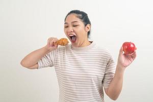 Mujer asiática con pollo frito y manzana en la mano foto