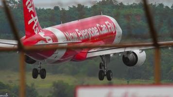 PHUKET, THAILAND NOVEMBER 26, 2017 - Airbus A320, HS BBG of AirAsia landing, touching the runway and braking at Phuket airport. View of the strip through the fence. Tourism and travel concept video