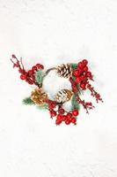 Red berries with fir branches and cones. Christmas wreath on white background with snow. New year card. Copy space photo