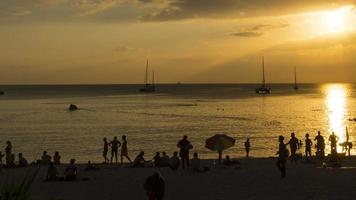 Scenic seascape timelapse on Phuket island at dusk with boats, yachts and people at the beach and surfing in water video