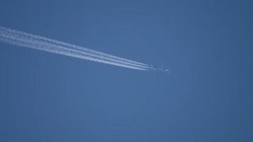 scie di condensazione nel cielo azzurro di agosto. aereo che vola alto. video