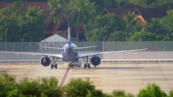 PHUKET, THAILAND NOVEMBER 29, 2019 - GoAir Go Airlines Airbus A320 VT WGB being pushed back by tow truck before departure. View from the top floor of the hotel near airport video