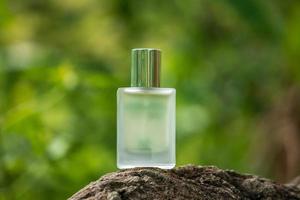 Perfume bottle on stone on green background photo