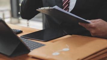 Business and lawyers discussing contract papers with brass scale on desk in office. Law, legal services, advice, justice and law concept picture with film grain effect video