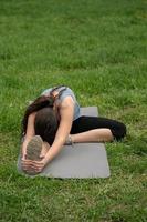 aptitud física. niña sentada en el césped en el patio de su casa, haciendo impuestos especiales. foto