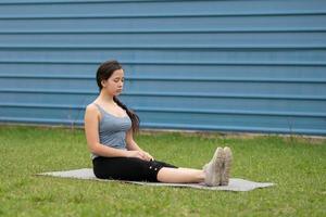 Fitness. Girl sitting on the lawn in the yard of her house, doing excise. photo