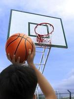 el aro de baloncesto y el niño anotan un punto foto