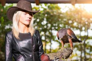 Beautiful blond woman holding an harris hawkon a protective glove photo