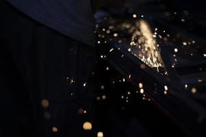 Metal grinding. Sparks from friction. Lights in dark. Chaotic flight of partial fire. photo