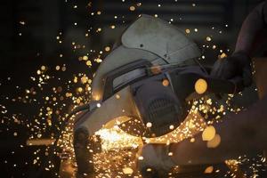 Sawing metal with circular saw. Work in garage. Sparks from steel. photo