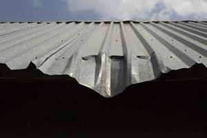 Dent on roof. Bent metal profile. Roof of building. photo