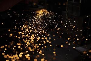 Sparks from grinding metal. Bright lights in dark. Cutting steel. Metal profile processing. photo