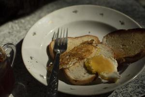 Bread and egg on plate. Breakfast on table. Details of ordinary food. Fork and plate in kitchen. photo