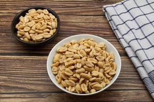 Pealed Peanuts in a bowl isolated on wooden background photo