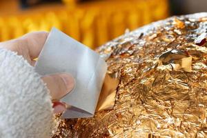 hand of buddhist gilding gold leaflet on golden ball in temple photo