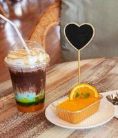 close up cold mixed cocoa, orange cake and spoons on wooden table photo