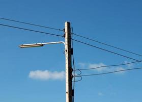 poste eléctrico con cable sobre cielo azul foto