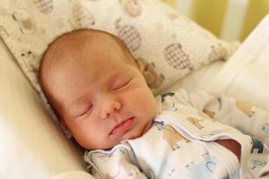 Cute newborn baby is sleeping on her bed. photo